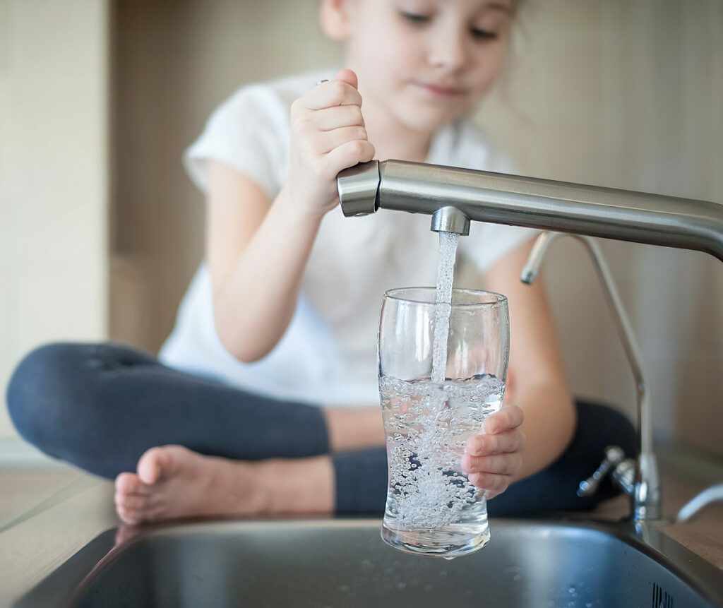 Young girl getting water from a tap